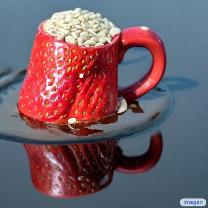 Una taza de fresa rellena de semillas de sesamo blanco, la taza flota en un mar de chocolate negro